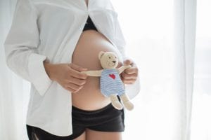 Ontwikkeling baby, zwangere buik met knuffelbeer